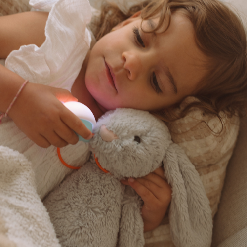 Child winding down with Snuggo glowing on a plush bunny